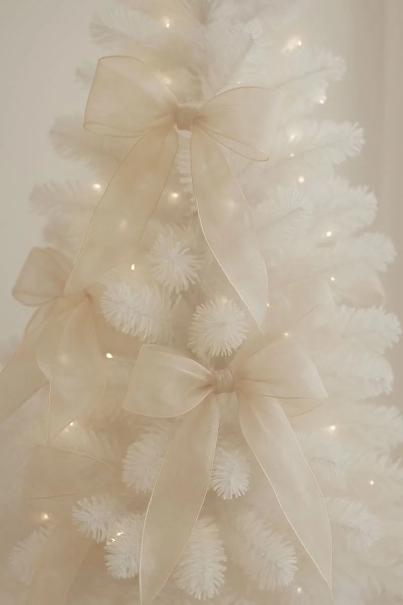 neutral sheer organza ribbon bows decorating a white minimalist Christmas tree