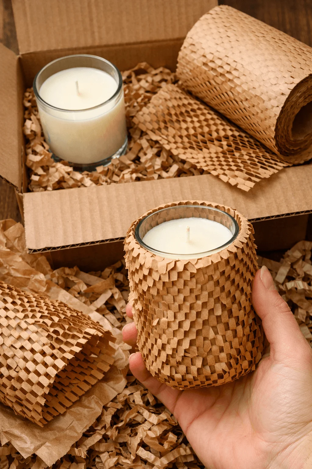 Candles protected with expandable honeycomb paper wrap inside a cardboard box filled with shredded paper for eco friendly cushioning