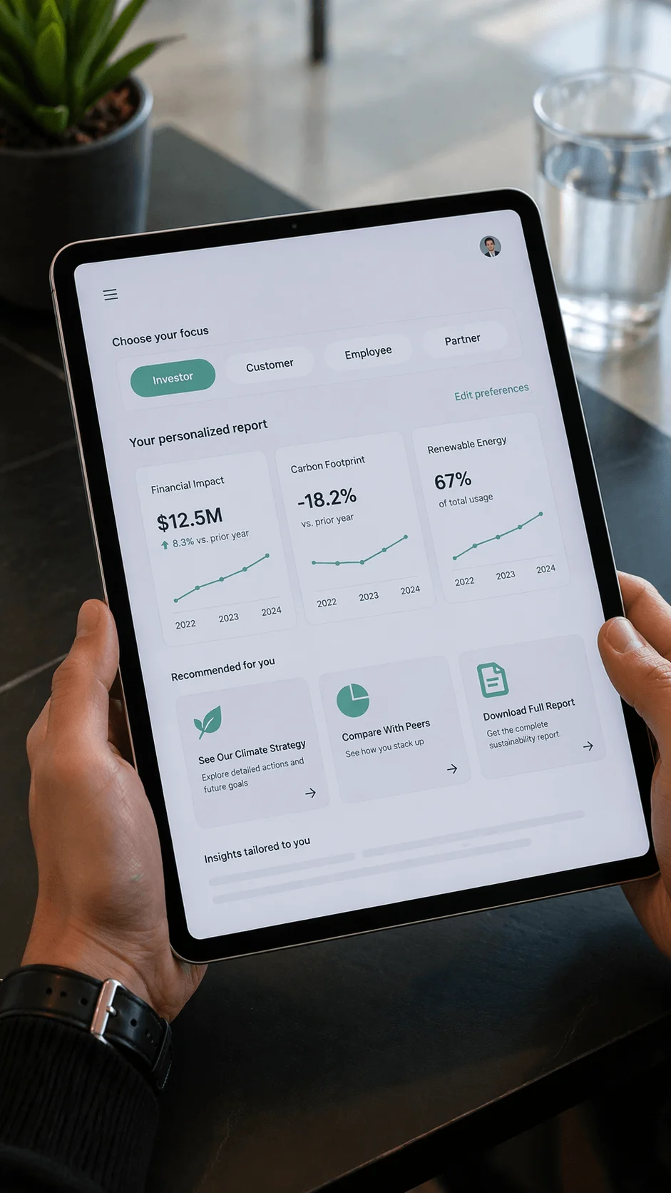 Person holding a tablet displaying a personalized sustainability dashboard for investors showing financial impact of 12.5 million carbon footprint reduced by 18.2 percent renewable energy usage at 67 percent and options to explore climate strategy compare with peers and download the full report