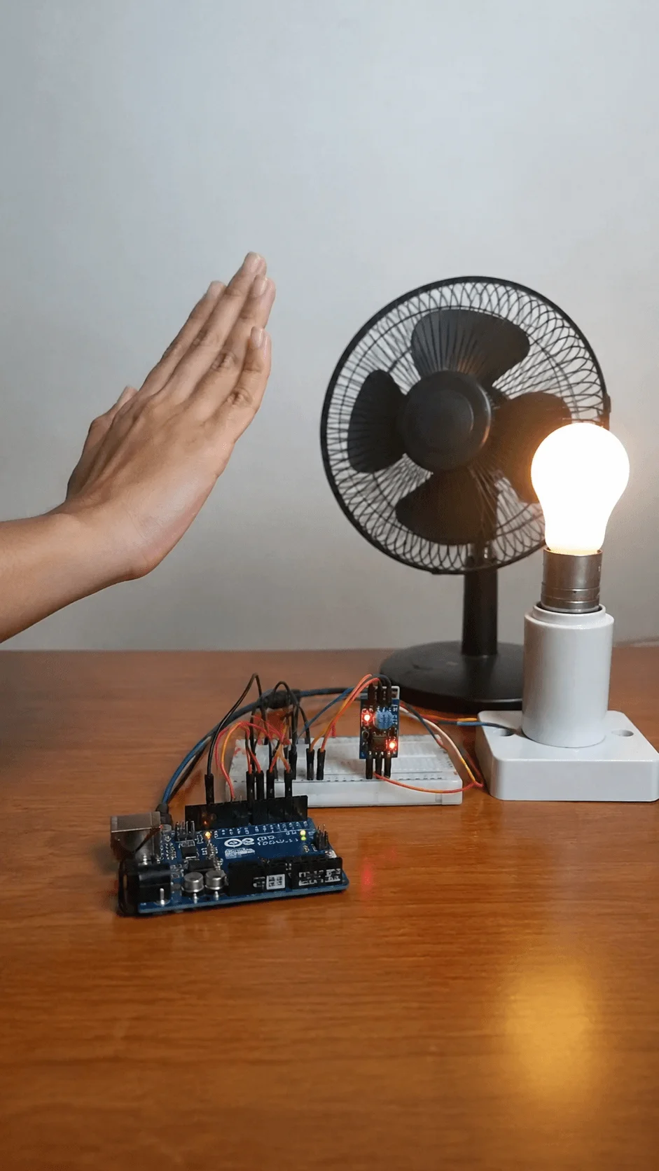 Gesture controlled smart device system using Arduino and motion sensors to control a light bulb and fan with hand gestures on a tabletop setup