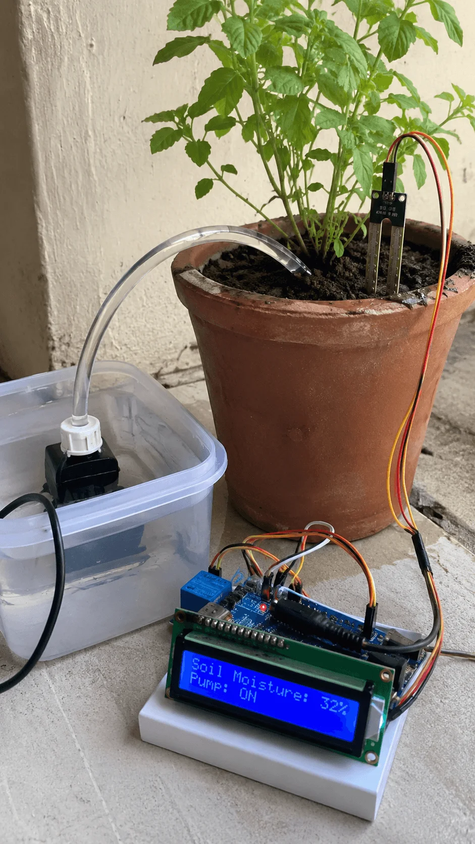 Smart plant watering system using soil moisture sensors Arduino controller and water pump to automatically irrigate a potted plant based on soil moisture levels displayed on a digital screen