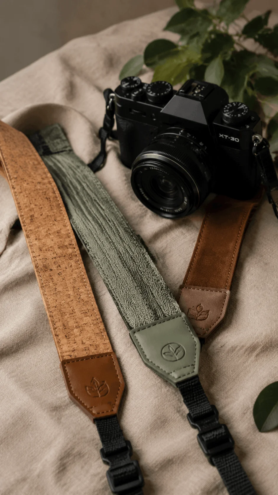 Eco friendly camera straps made from sustainable materials with a mirrorless camera arranged on soft fabric and surrounded by natural greenery