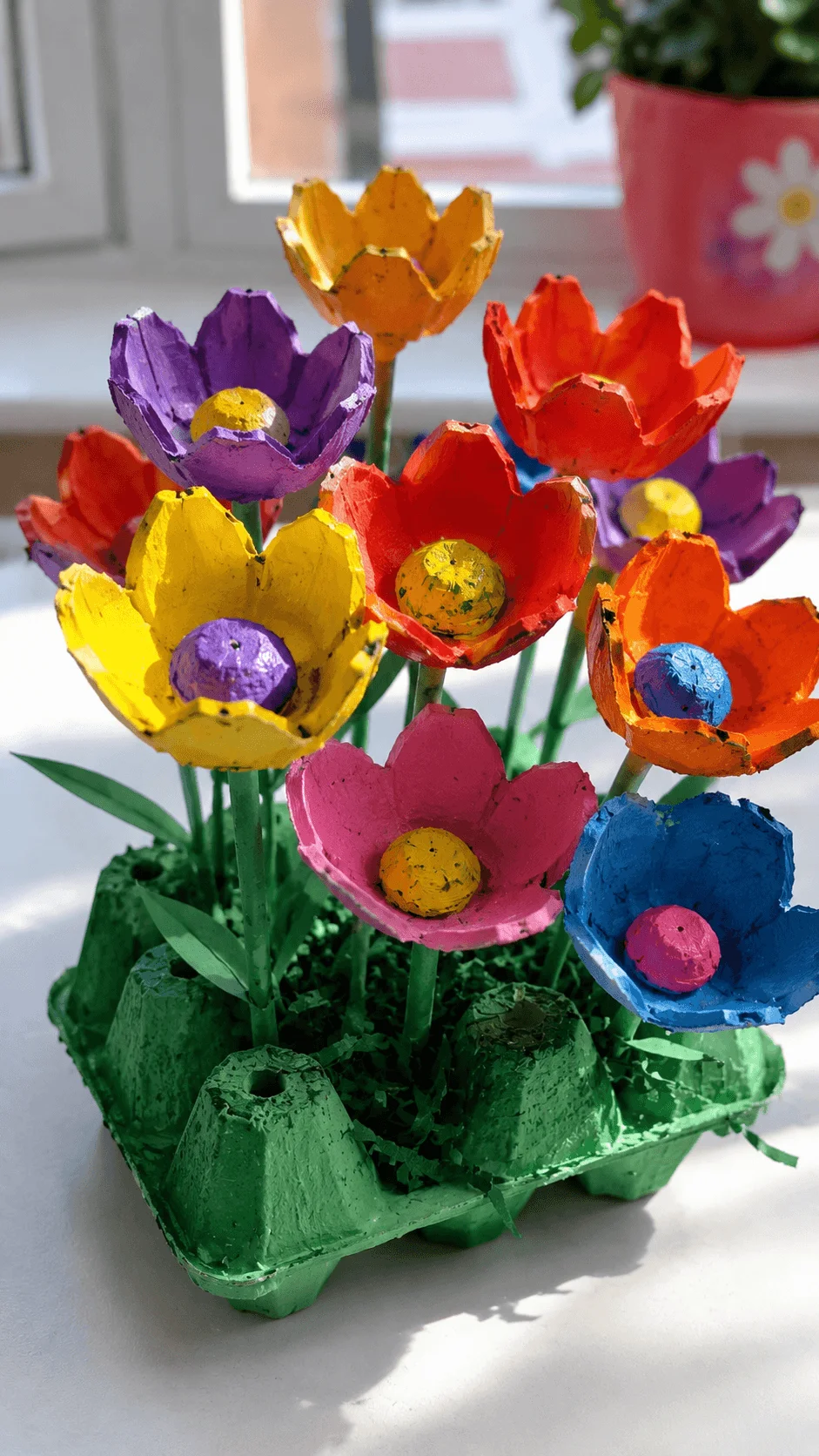 Egg carton flower garden craft featuring brightly painted recycled egg carton flowers arranged in a colorful bouquet with green stems and leaves displayed in a reused carton base as a creative eco friendly art project for kids.