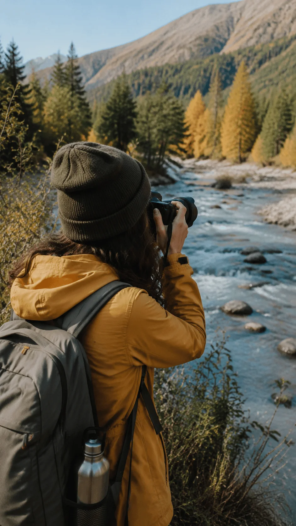 Photographer capturing a mountain river landscape during a local outdoor adventure with backpack and camera surrounded by nature