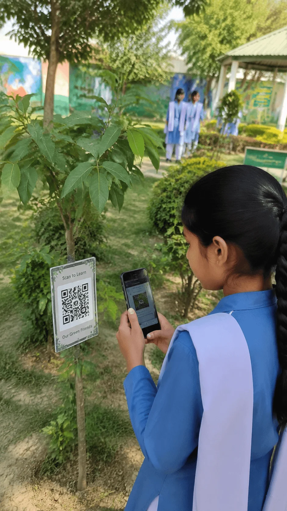 Student scanning a QR code nature trail sign on a school campus to learn about trees plants and environmental features through digital education