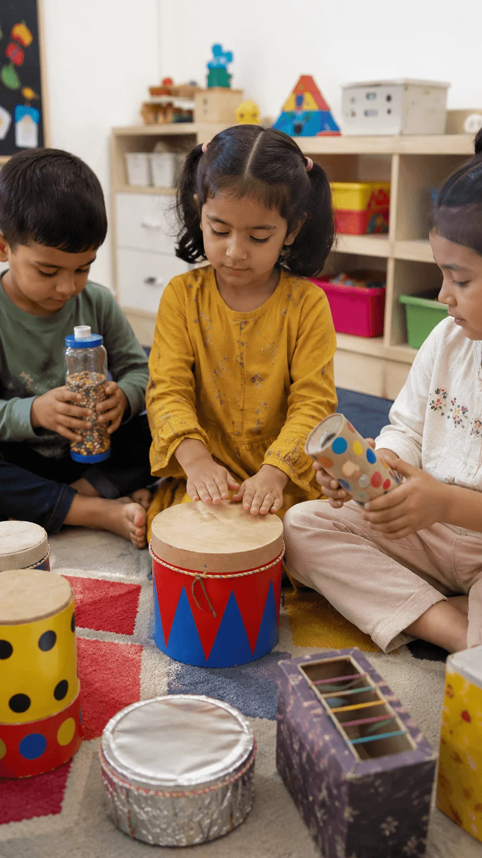 Children creating recycled music makers using handmade drums and shakers from reused materials during a preschool sustainability activity