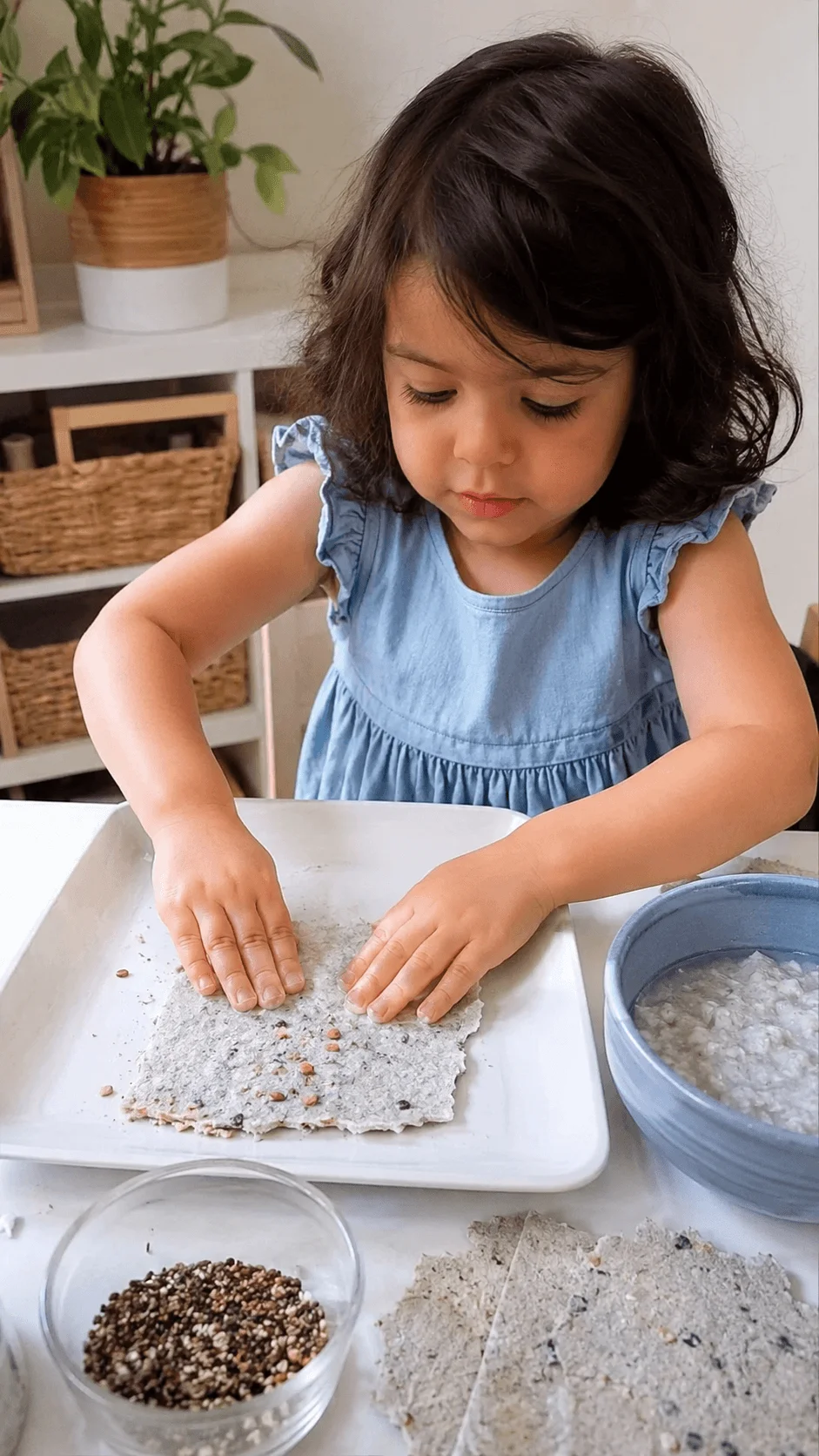 Preschool girl making seed paper by pressing recycled paper pulp and seeds into a flat sheet