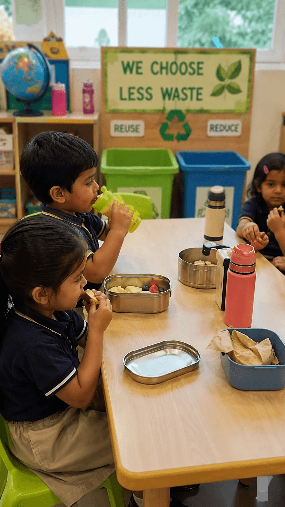 Preschool children enjoying a zero waste snack time with reusable lunch containers and water bottles while learning to reduce everyday waste.