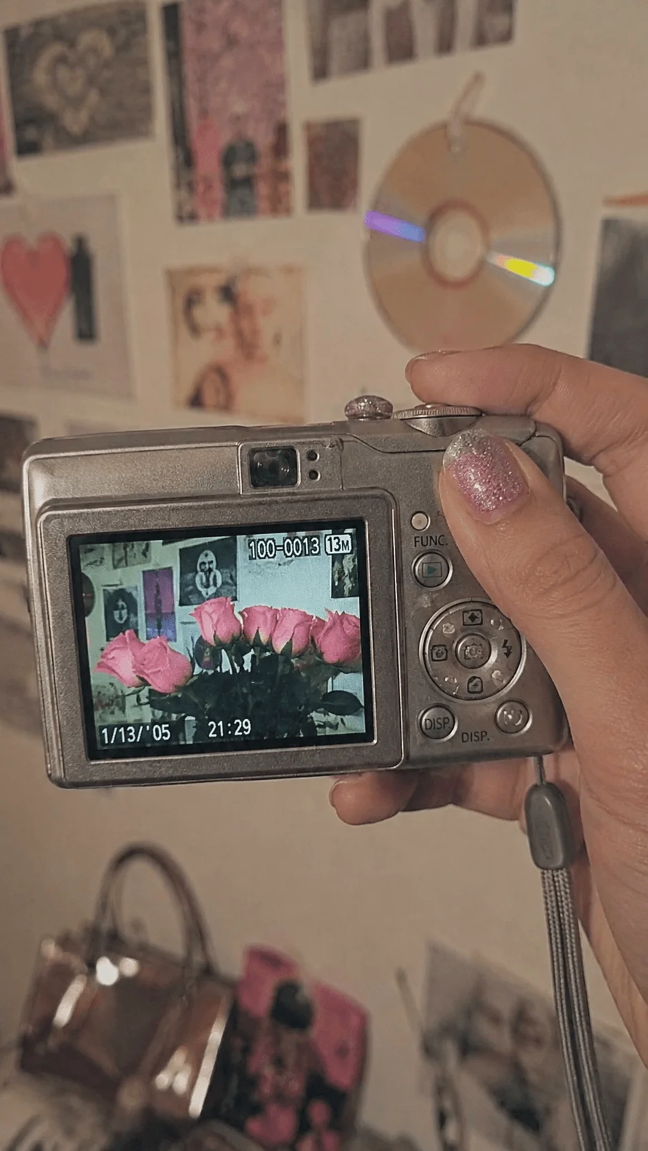 Y2K digital camera held in hand displaying a photo of pink roses with a nostalgic retro aesthetic