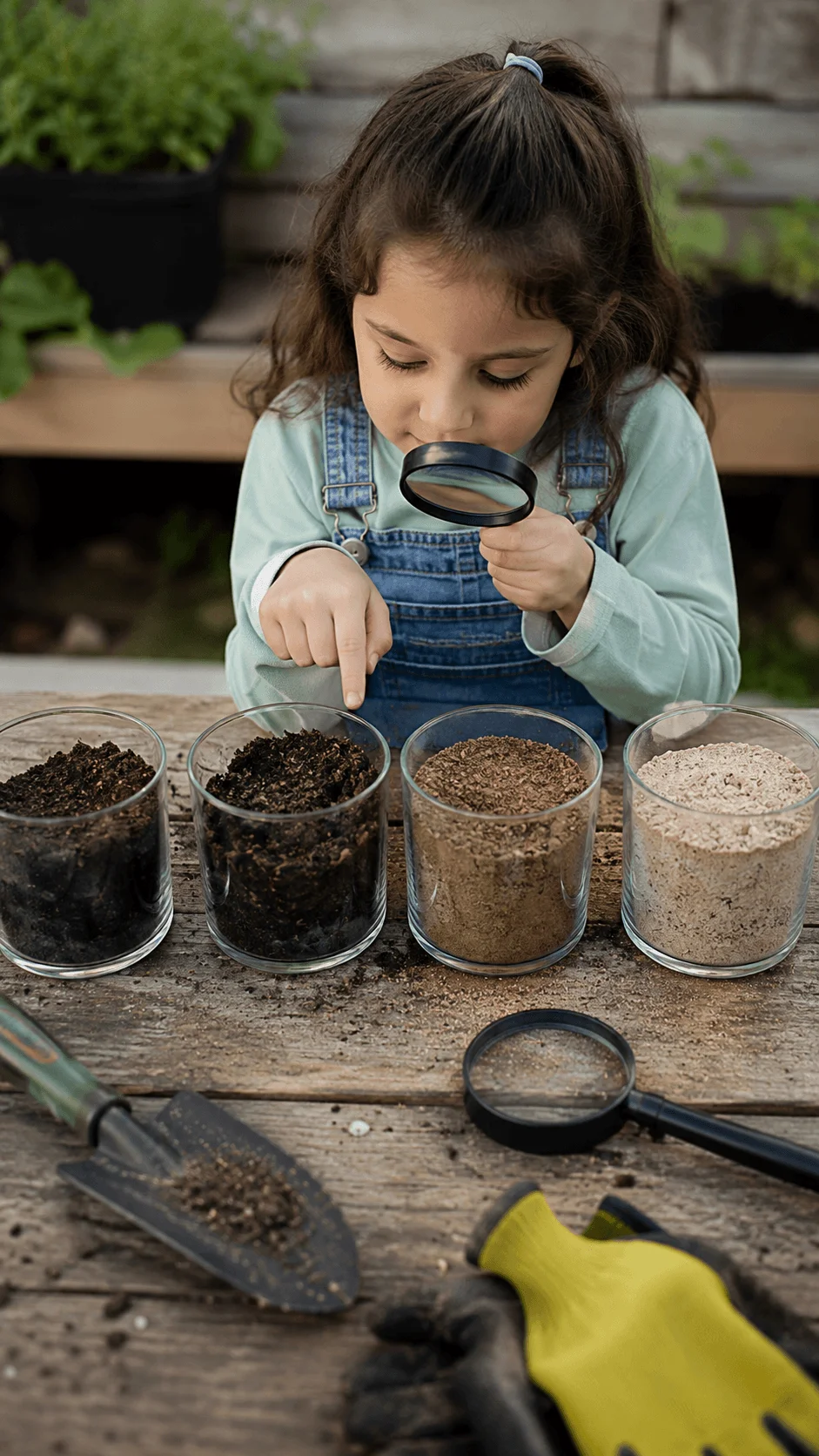 Child exploring different soil types with a magnifying glass during a hands on soil discovery activity