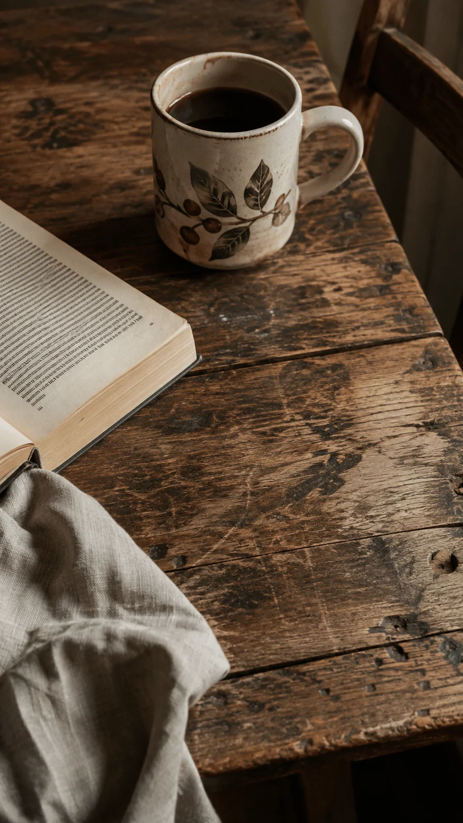 Imperfect and authentic photography featuring a vintage ceramic coffee mug, open book and linen cloth on a weathered wooden table with natural warm light