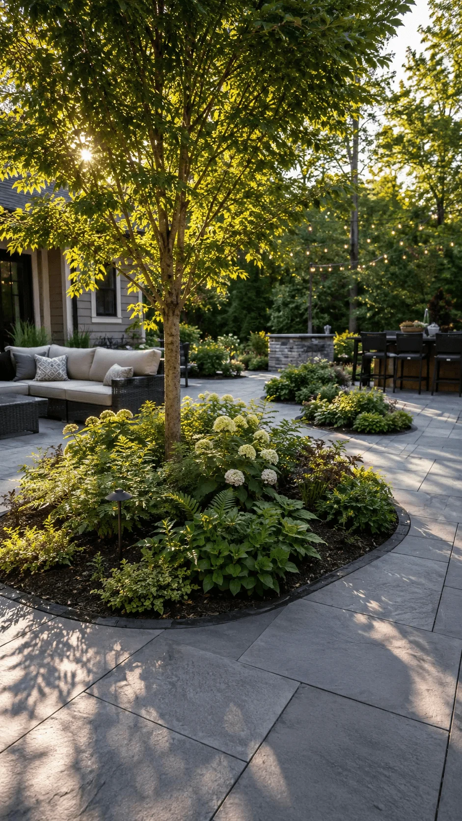 Eco friendly patio island planting with shade tree lush greenery flowering plants natural stone paving and outdoor seating area