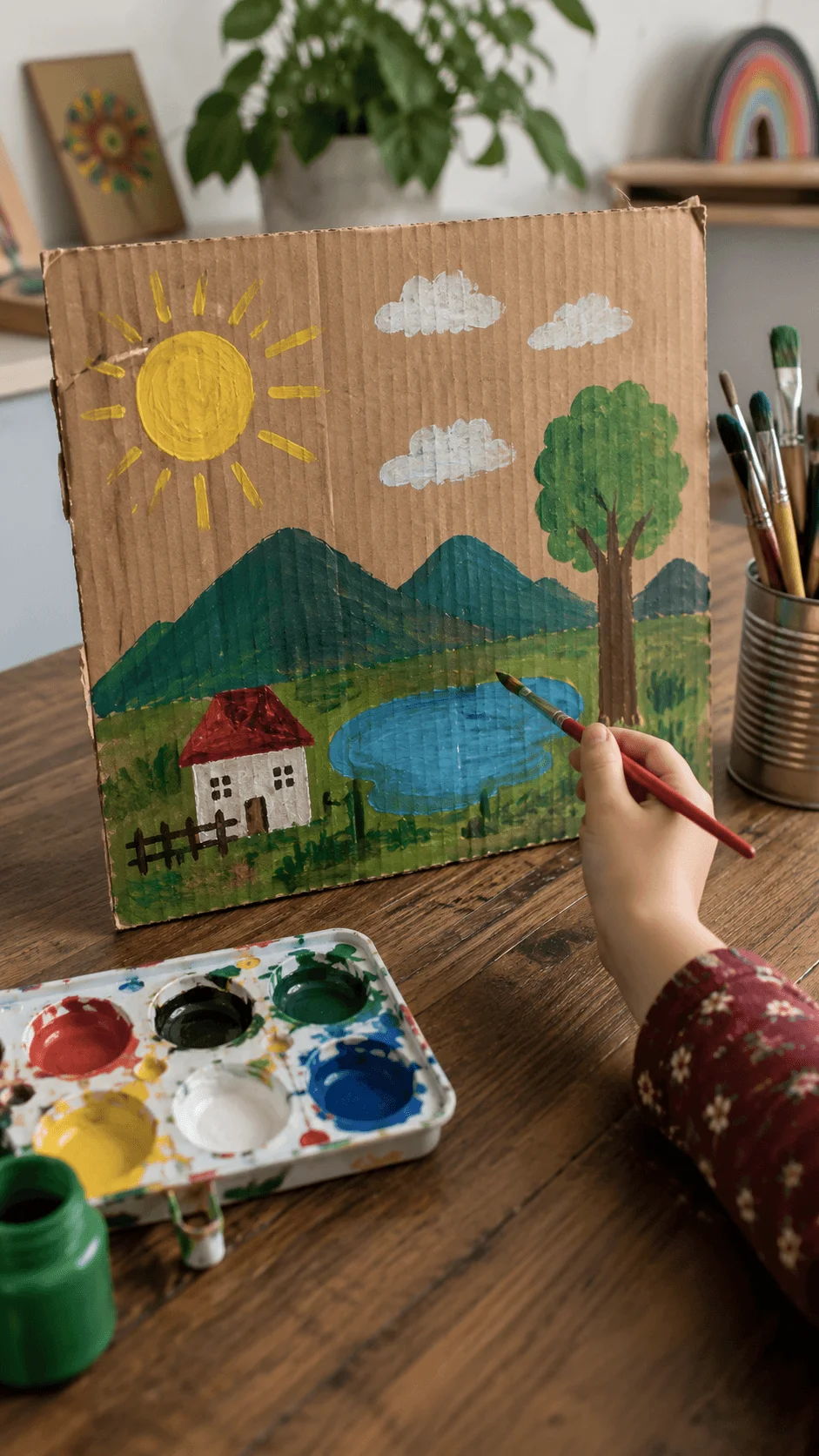 Recycled cardboard painting ideas for kids with a child painting a colorful nature scene on recycled cardboard