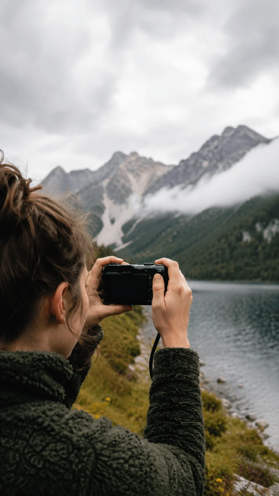 Person using a screen free camera to photograph a mountain lake and surrounding landscape