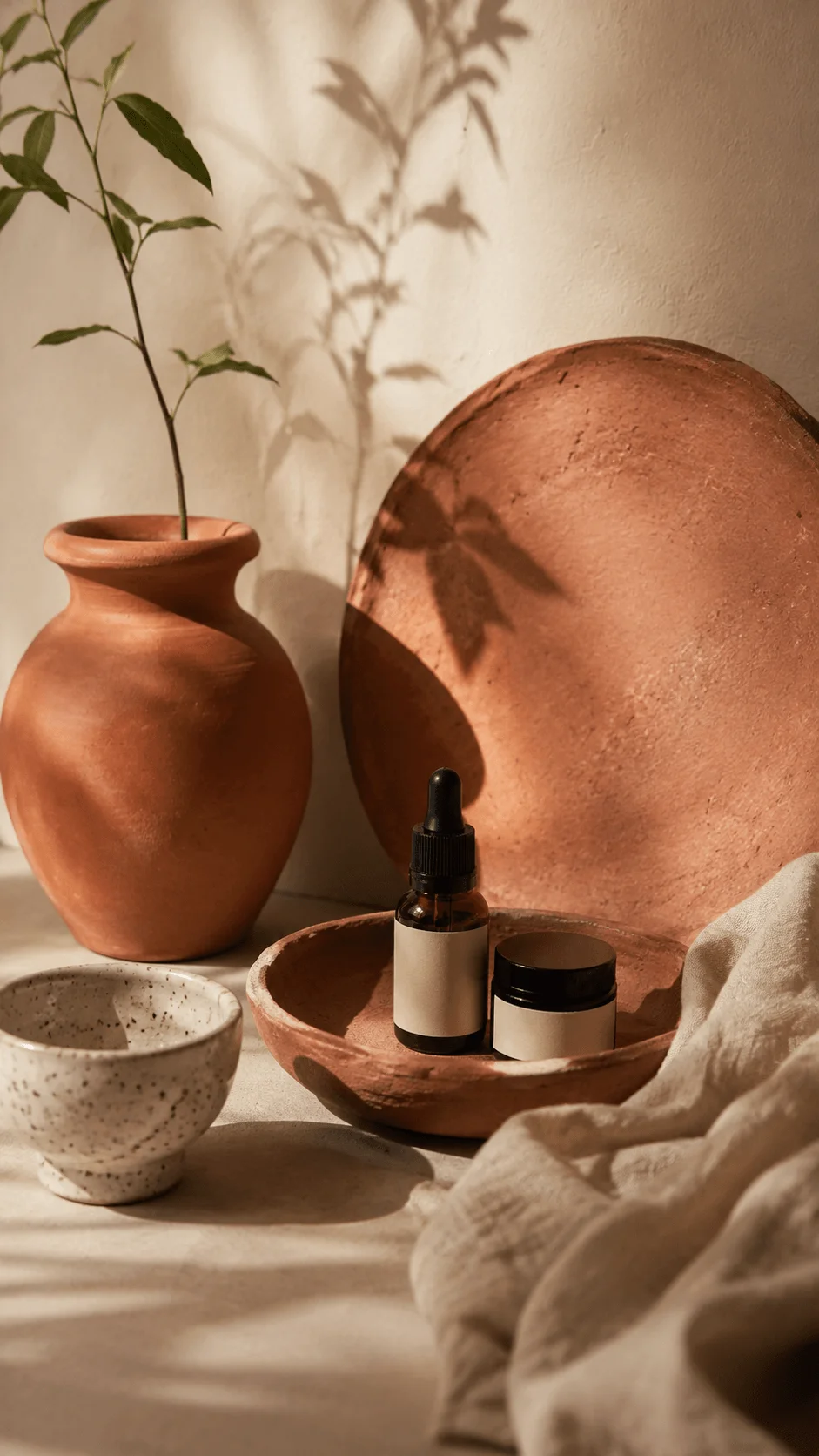 Terracotta and natural clay photography props featuring clay pots, ceramic bowls, skincare containers, a leafy plant, and warm earthy tones with natural light