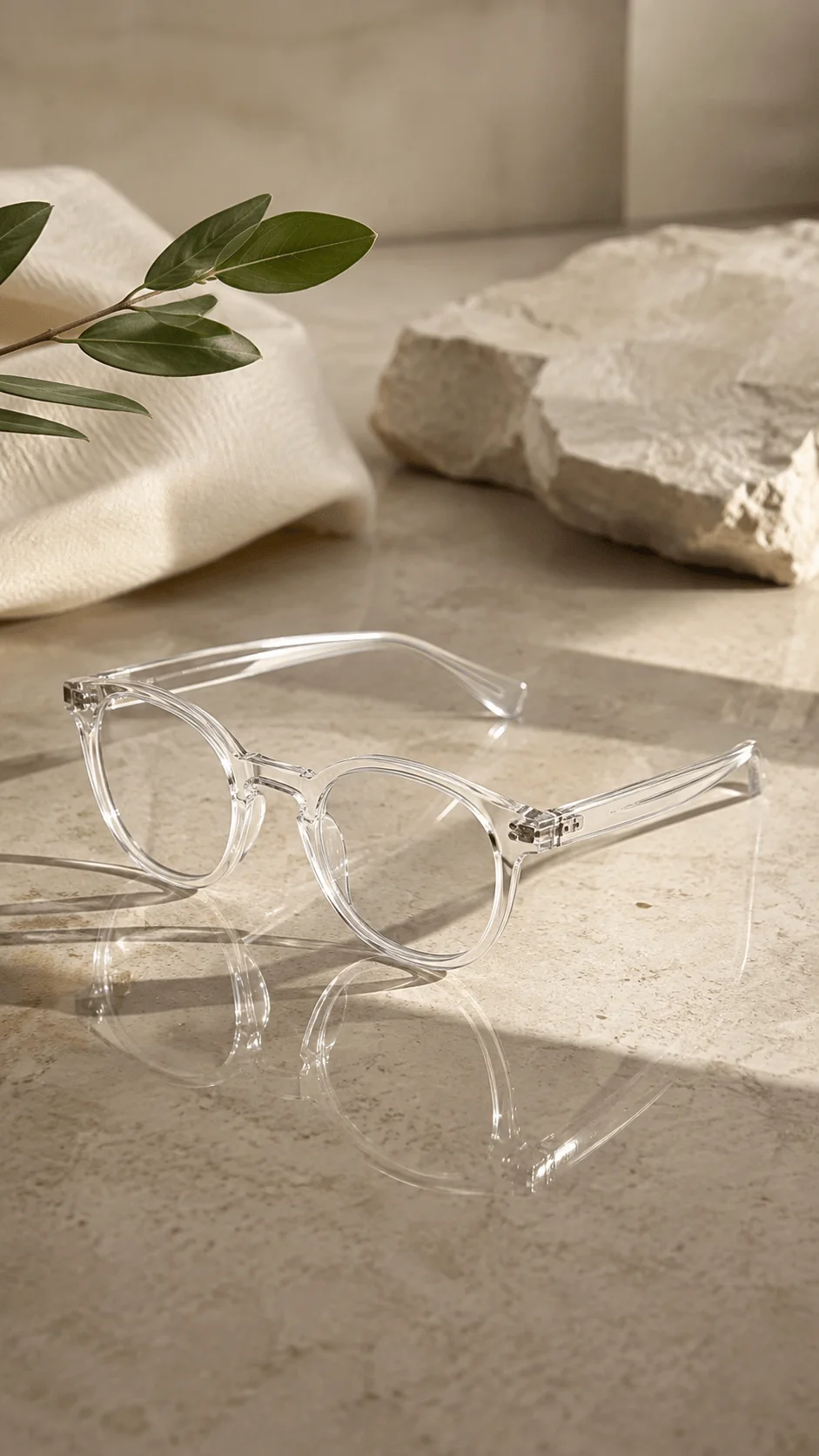 Transparent eco friendly glasses on a stone surface with natural sunlight, greenery, and textured neutral decor